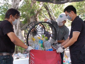 快樂公司董事長王燦榮（中著灰衣者）和員工一起將數好的保特瓶裝入袋內打包，上下一心，一起為環保付出。（攝影者：吳嘉博 地點：關渡志業園區 日期：2010/10/06）