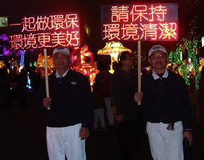 穿著藍天白雲的慈濟志工，夜色中拿著主辦單位提供的紅色LED燈的告示牌，穿梭在人群中。（攝影者: 羅鳳琴，地點:竹南運動公園，日期:2011/02/17）