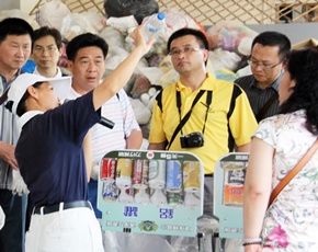 慈濟志工翻轉著寶特瓶底部，告訴來訪者如何分辨塑膠瓶的分類。(攝影者：黃吉和，地點：慈濟內湖聯絡處，日期：2011/06/28)
