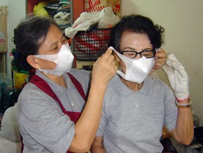 郭月娥（左）戴好口罩，再幫七十七歲的吳靜枝戴口罩，親切的法親情誼，讓她樂於天天做環保。（攝影者：白如璐 地點：新竹東門環保教育站 日期：2010/09/30）
